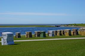 Colorful standing baskets on the beach of BÃ¼sum, Germany, with plants, under the blue sky with clouds