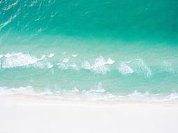 turquoise Sea waves splashing on white beach