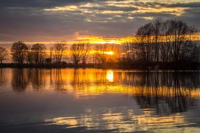 Beautiful landscape with the lake with ripple, among the plants, at colorful and beautiful sunset with clouds