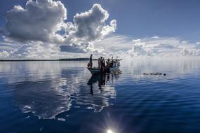 tribal people fishing on boat with net, indonesia, halmahera
