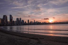 Beach of the city with buildings and water with ripple, at colorful and beautiful sunset