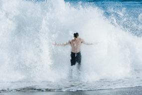 Man with bare chest, in the waves of water, on the beach