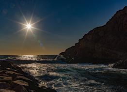 bright sun over a rocky coastline on a clear day