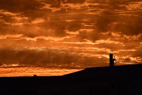 Landscape with silhouettes, at beautiful, orange sunrise in clouds