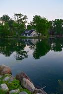 Beautiful landscape with the house on the shore with colorful stones and green trees