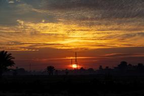 the setting sun on the horizon behind the trees