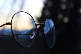 Close-up of the shiny, retro glasses in the forest, at colorful and beautiful sunset