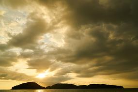 black clouds over silhouettes of tropical island