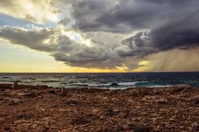 dramatic clouds over sea with rocky shore
