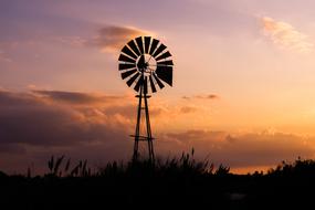 Beautiful landscape with silhouettes of the windmill and reeds, at colorful and beautiful sunset with clouds
