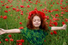 redhead girl posing on a field of red poppies