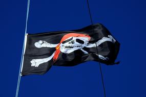 black pirate flag on a mast against a blue sky