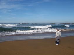 child on the sand near the waves