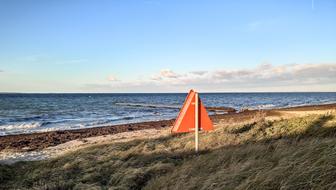 Red shield sign among the plants, on the coast of Baltic Sea in Denmark