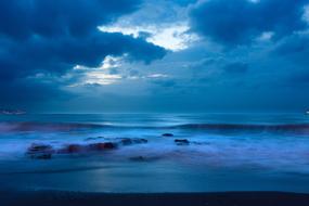 Beautiful beach of the sea, with rocks, under the clouds, in blue colors