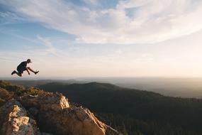 Person jumping on the beautiful and colorful mountain, at beautiful and colorful sunrise with clouds