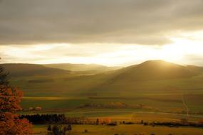 the setting sun behind the green hills in autumn