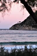 Beautiful landscape of the beach with mountains, plants and waves, at colorful and beautiful sunrise