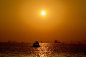 boat at sea against the background of yellow sky during sunset