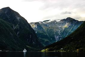 Beautiful Fjord with the ship on the water, among the green mountains with snow, in Norway
