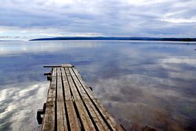 boardwalk pier on the sea with mirror reflection of clouds