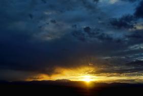 bright yellow sun in dark clouds at dusk
