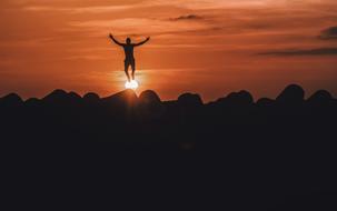 silhouette of a jumping man in the mountains at sunset