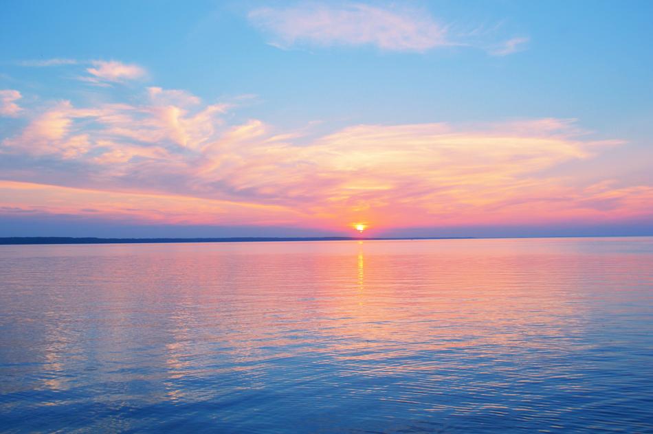 the setting sun on the horizon of the lake