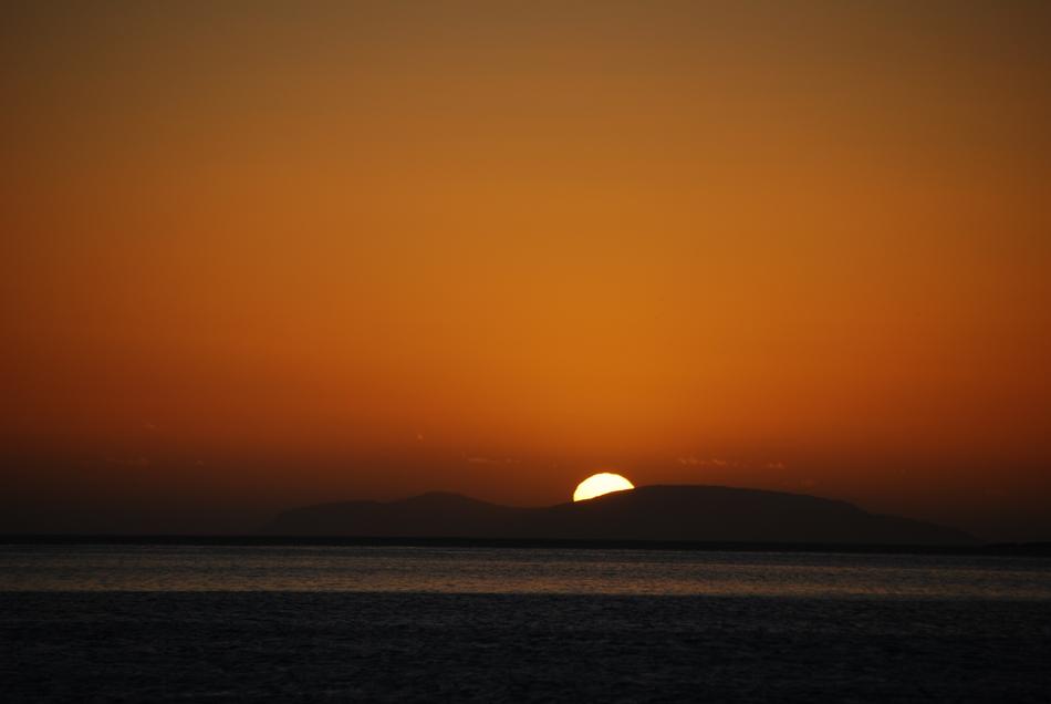 distant view of the setting sun over the mountains to the sea