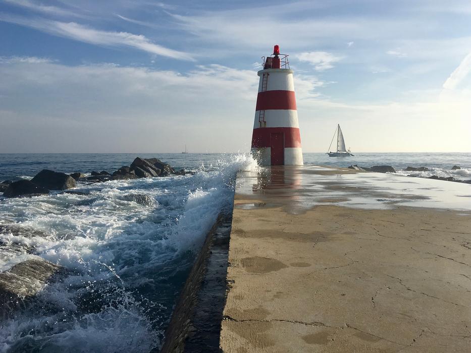 Beautiful pier with the red and white lighthouse, and splashes in the water