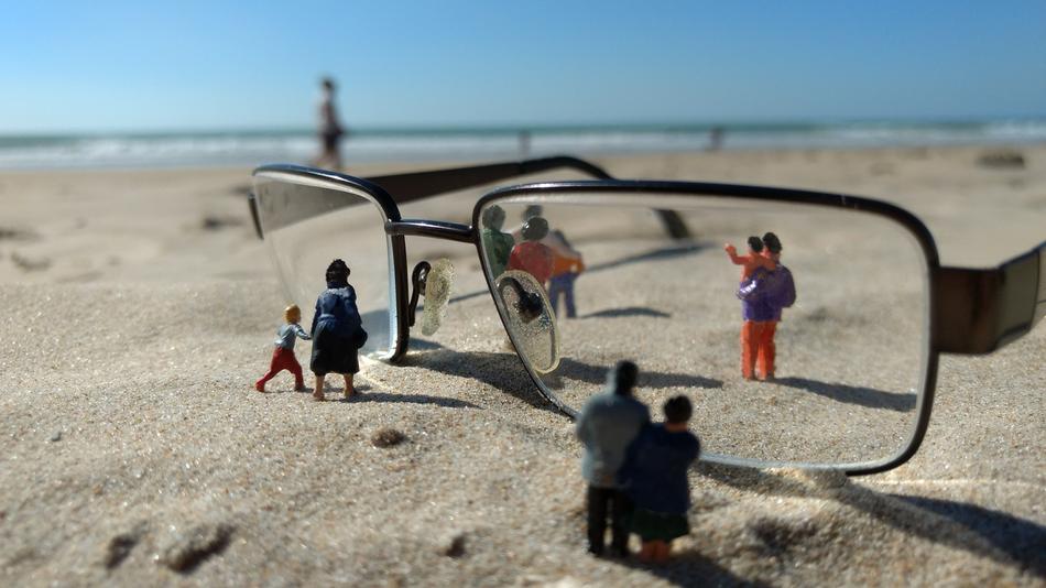 glasses and figures of people on the sand on the beach