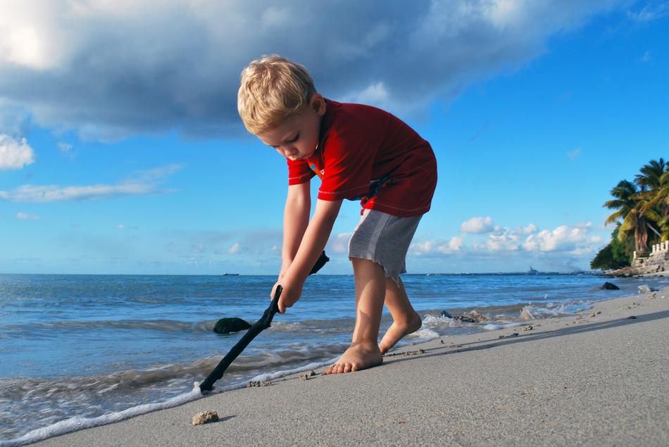 boy with stick on tropical beach