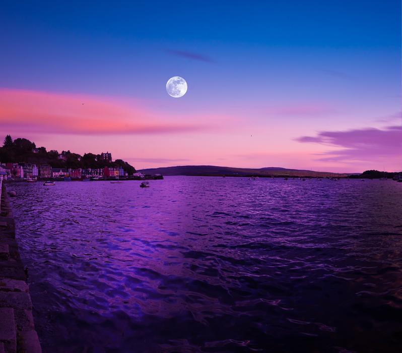full moon with purple glow over the ocean near the island