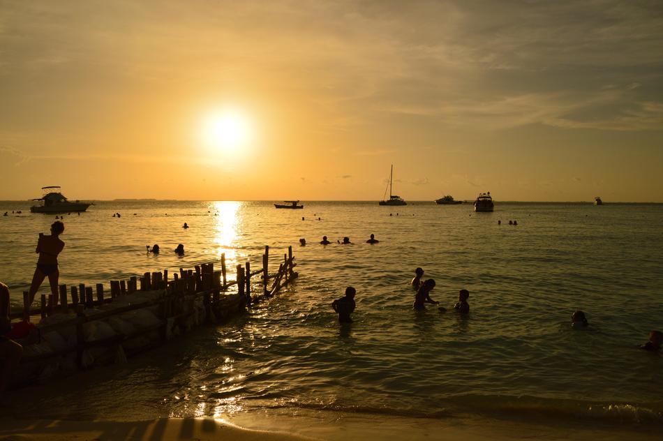 People in the water on the beach in Mexico at beautiful and colorful sunset