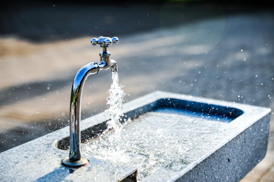 photo of a fountain with an open tap on the street