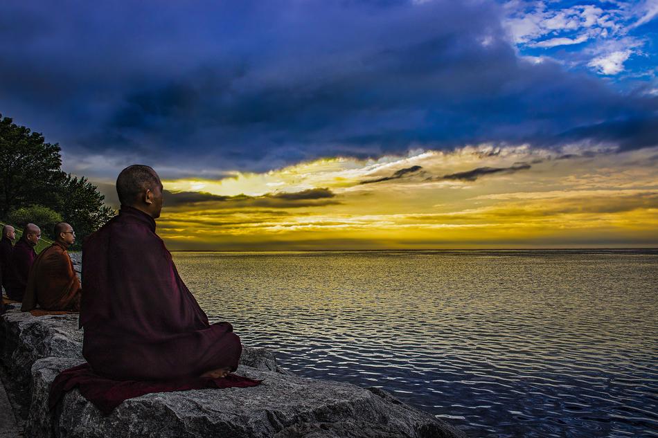 monk meditates on the lake at dusk