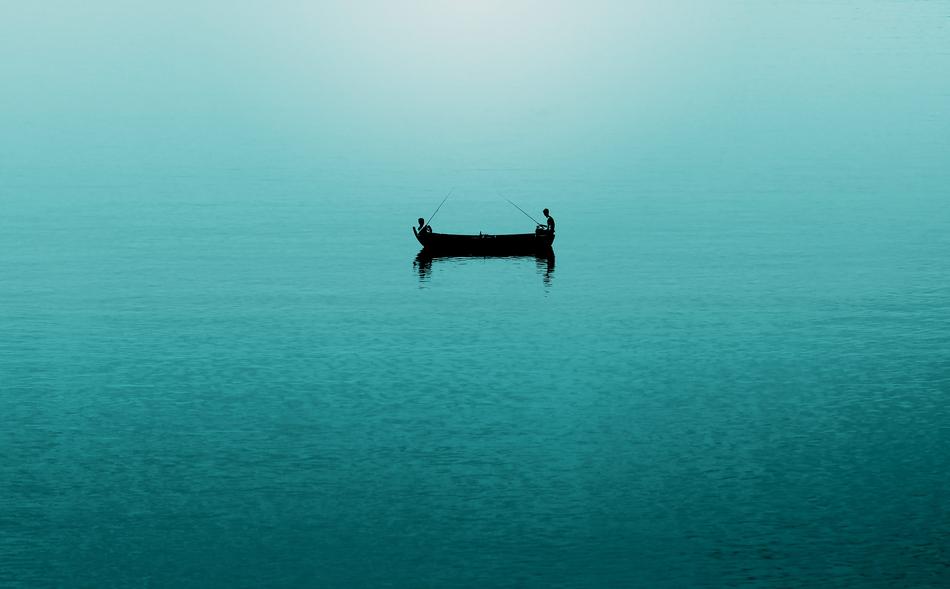 Silhouettes of the fishermen on the boat, among the beautiful, turquoise ocean
