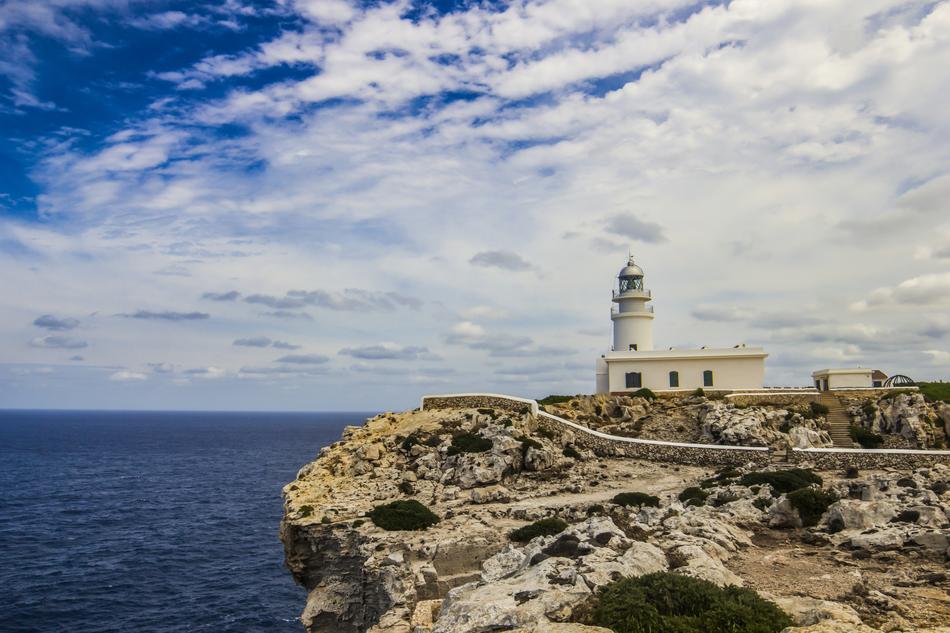 Beautiful Lighthouse of Horses, on the colorful rocky coast of Minorca, in Spain, under the blue sky with clouds