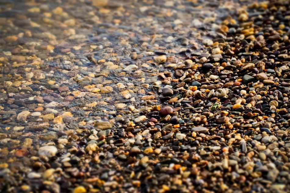 Beautiful and colorful pebbles in water, on the beach