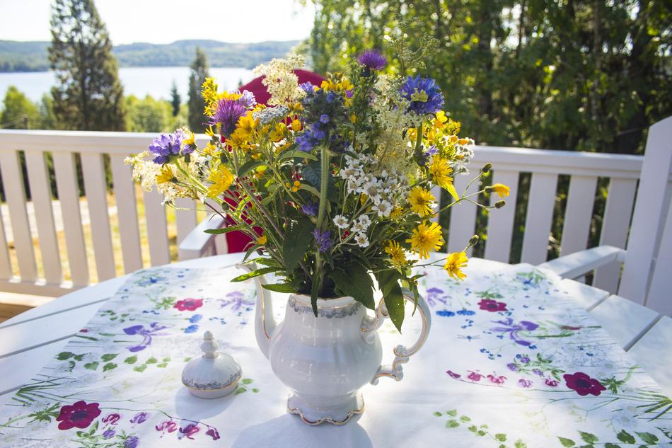 Close-up of the colorful and beautiful flowers, in the vase. on the table, with the colorful, patterned cloth