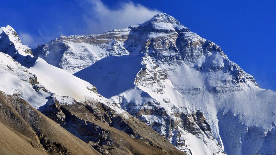 Beautiful, snowy Mount Everest in Tibet, in sunlight, under the blue sky with clouds
