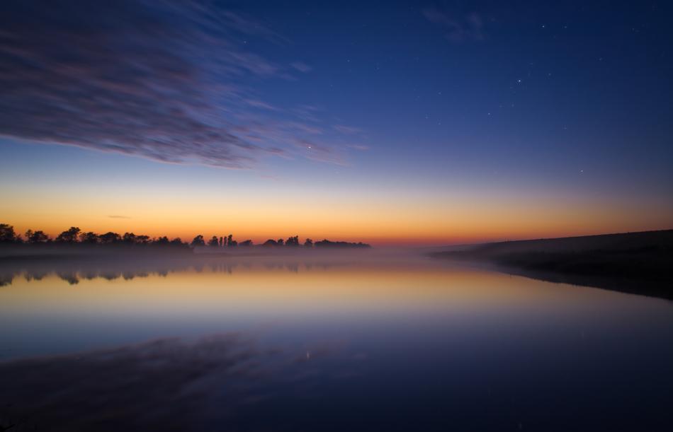Beautiful and colorful landscape with the lake, among the trees, at colorful twilight