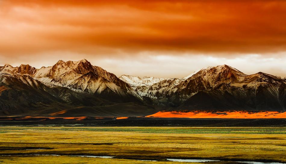 Beautiful and colorful panorama with the field near the mountains in snow, in California, USA, under the colorful sky with clouds