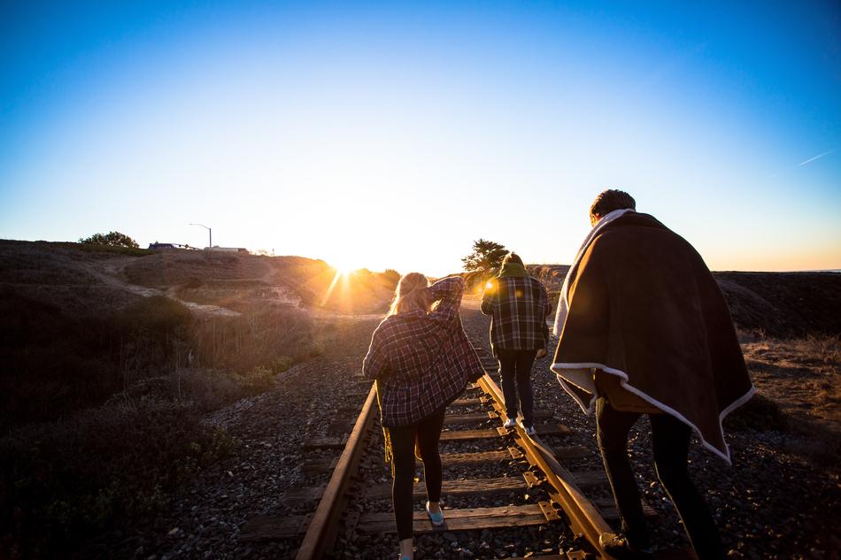 people walking on railway rails in the background of sunset