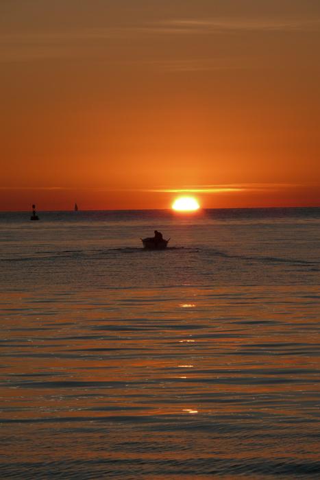 Fisherman on the boat, on the sea, at colorful and beautiful sunset