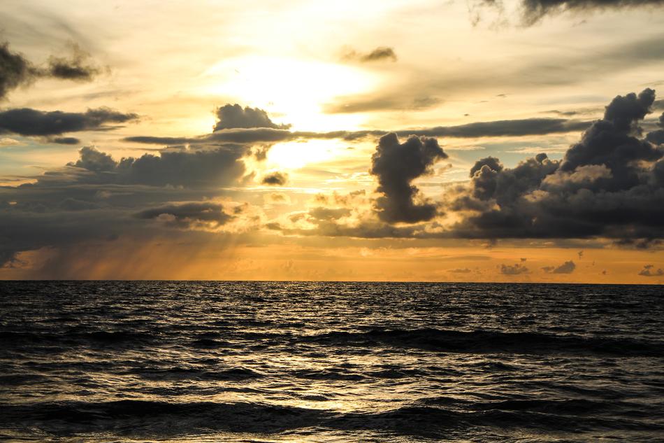sunset in the clouds over the sea waves