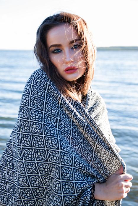 Portrait of the beautiful girl in the colorful, patterned cloth, near the water, at colorful and beautiful sunset