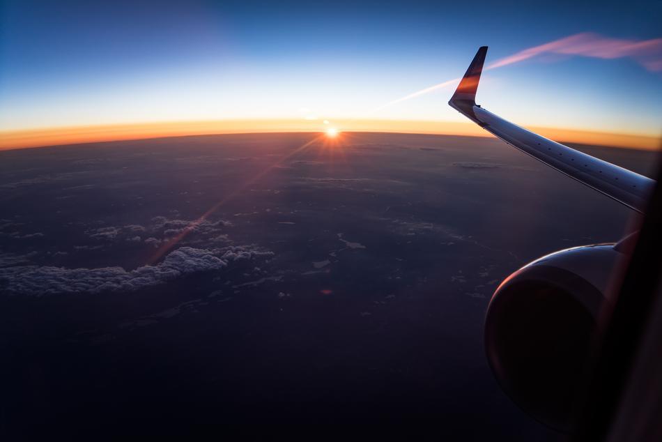 the plane flies in the sky during sunset