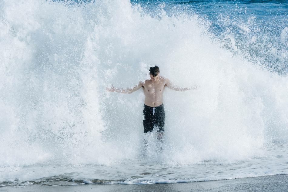Man with bare chest, in the waves of water, on the beach