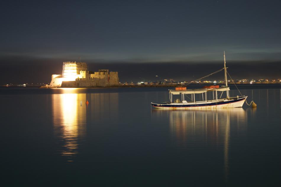 Boat on the water, near the beautiful castle with light, in Greece